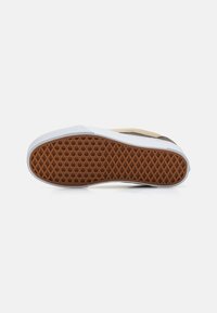 Sneaker sole featuring a honeycomb pattern in brown rubber, bordered by white plastic. The design is flat and slightly curved at the heel.