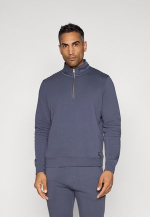 Námornícka modrá mikina na zips s vysokým golierom, vyrobená z jemnej tkaniny, so strieborným zipsom a rebrovanými manžetami a lemom.
