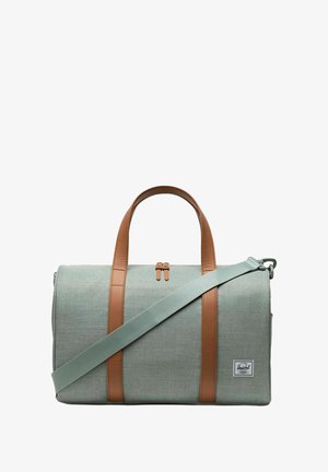 Sac de voyage en tissu gris avec des poignées et des accents en cuir marron. Comprend une bandoulière amovible et une fermeture à glissière. Logo de la marque visible.