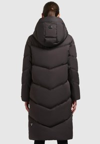 Long, dark gray puffer coat with a hood. Features chevron pattern stitching, a logo patch on the back, and sleek, minimal design.
