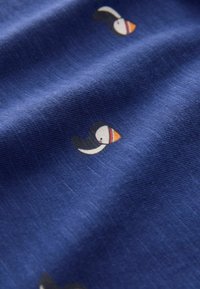 Blauer Stoff mit kleinen abstrakten Vogeldesigns in Farben wie Orange, Weiß und Schwarz. Das Material wirkt strukturiert mit einer weichen Oberfläche.