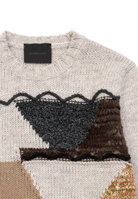 Maglione lavorato a maglia spesso con base crema, caratterizzato da vivaci motivi geometrici a patchwork in nero, marrone e beige. Dettagli con bordo scallop.