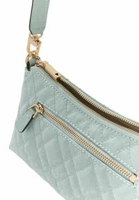 Sac à main matelassé bleu clair avec ferrures dorées, doté de deux fermetures éclair et d'une surface texturée. Sangle réglable pour un port polyvalent.