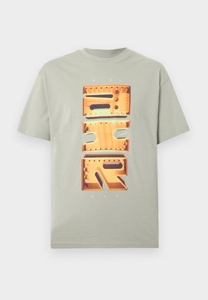 Svetlo siva kratka majica s kratkimi rokavi z veliko navpično grafiko NIKE AIR v oranžnem kovinskem slogu ter majhnim napisom "NIKE MAX" nad in pod grafiko.