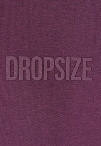 Violetinio audinio fonas su tekstūruotais, iškiliais rašmenimis, rašančiais "DROPSIZE" šiek tiek tamsesniu violetinės spalvos atspalviu.