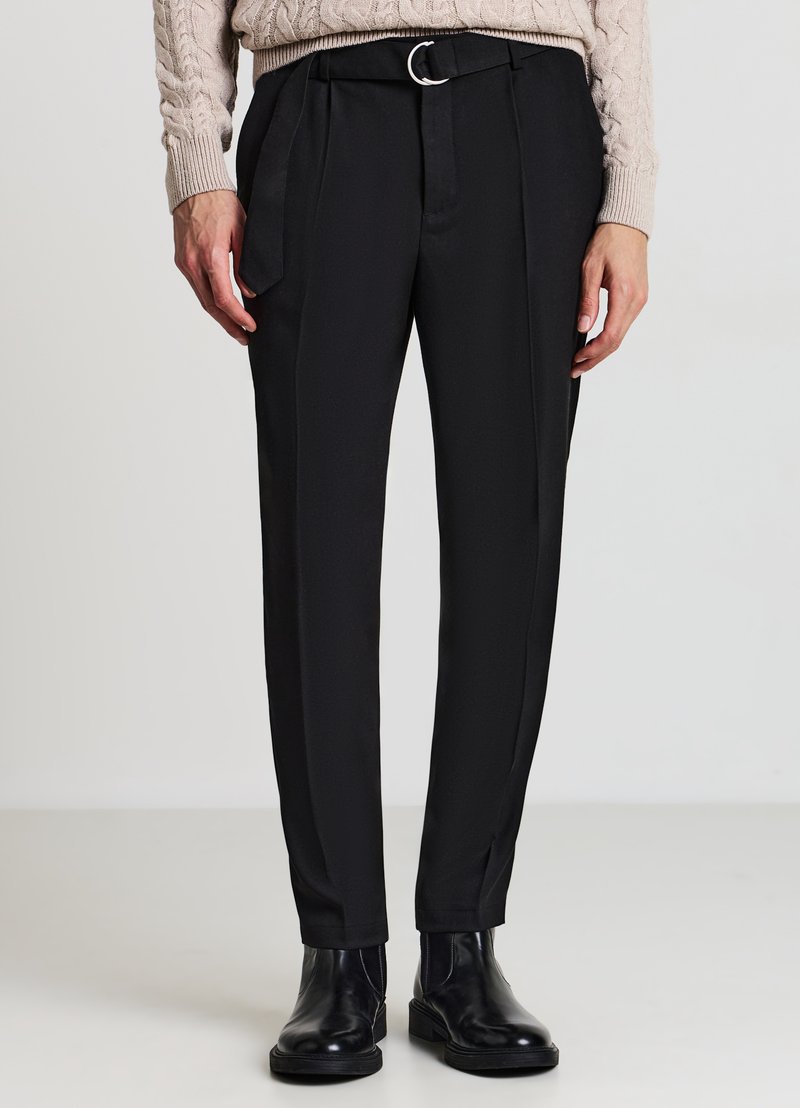 Pantaloni neri su misura con una texture liscia, dotati di cintura con fibbia circolare argento, tasche laterali e design slim-fit.