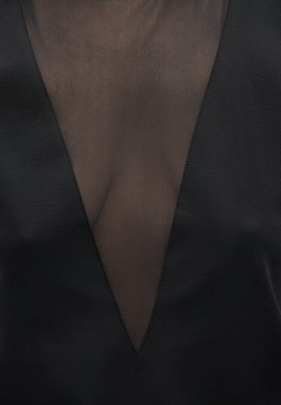 Sort beklædningsgenstand med et dybt V-formet gennemskinneligt meshpanel ved brystområdet, der skaber en kontrast mellem ugennemsigtigt stof og transparent materiale.