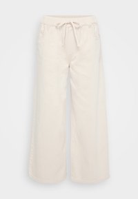 Pantalones de pierna ancha en algodón beige con cintura elástica y cordón. Cuenta con dos bolsillos frontales y una textura suave.