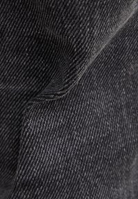 Primer plano de una tela gris oscuro con un tejido texturizado; presenta líneas sutiles y un acabado suave, sugiriendo durabilidad y comodidad.