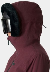 Giacca cappuccio bordeaux con fodera in pelliccia sintetica nera, chiusura con zip e colletto alto. Presenta un cordino regolabile nel cappuccio.