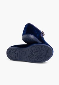 Zapatos de terciopelo azul marino con punta redonda y detalle de hebilla. La suela de goma presenta patrones florales y de corazones para tracción y diseño.