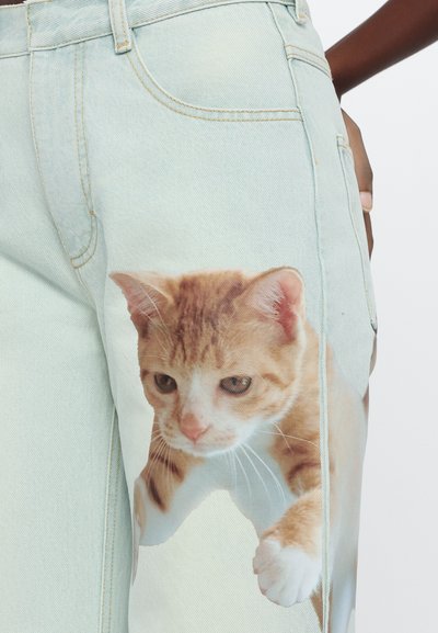 Lichtblauwe denim jeans met een groot afgebeeld beeld van een oranje tabby kat op het linkerbeen. Bevat een traditionele vijfzakkenontwerp.