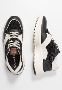 Černé a béžové tenisky s síťovaným svrškem se vzorem loga, koženými akcenty a strukturovanou gumovou podrážkou. Design na šněrování.
