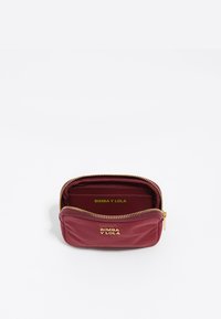 Funda con cremallera de color burdeos, hecha de material suave, con acentos de logotipo dorado y un pequeño compartimento interior. Las dimensiones son compactas y rectangulares.