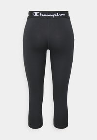 Czarne sportowe leginsy capri z wysokim pasem ozdobionym białym logo, wykonane z elastycznego materiału, z bocznymi kieszeniami.