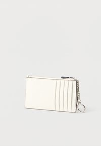 Cartera de cuero blanco con acabado texturizado, con ranuras para tarjetas y cierre de cremallera. Incluye una cadena plateada y un adorno de anillo.