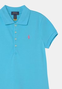 Vaaleansininen pikeepaita, jossa on teksturoidusta kankaasta valmistettu klassinen kaulus, kolme nappia ja pieni vaaleanpunainen brodeerattu logo.