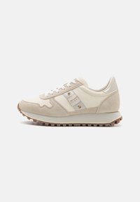 Beige athletic shoes with a mix of suede and leather, featuring seasonal rubber sole, white laces, and overlapping design accents.