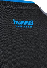 Zwarte sportkleding met een gestructureerde stof, met een blauw logo dat "hummel SPORTSWEAR" aan de achterkant van de nek leest.