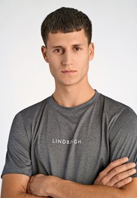 Szara koszulka z krótkim rękawem z białym logo "LINDBERG", wykonana z teksturowanego materiału, z okrągłym dekoltem i standardowym krojem.