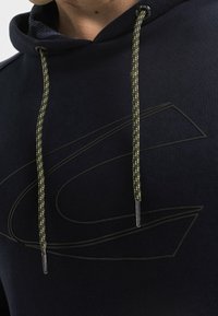 Granatowy sweatshirt z kapturem o teksturowanym wykończeniu, z kontrastującymi neonowymi żółtymi sznurkami i subtelnym tłoczonym wzorem z przodu.