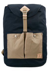 Granatowy plecak z brązowymi przednimi kieszeniami, materiał kanwasowy, zapięcie na klapę, metalowa klamra i skórzana naszywka z logo na dole.