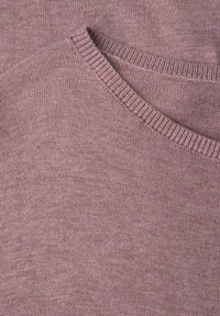 Primo piano di un maglione a maglia mauve chiaro, con scollo rotondo e una texture fine, arricchito da dettagli a coste sul collo.