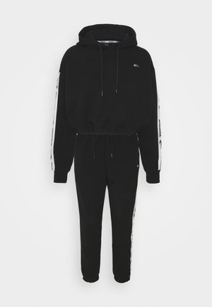 Black two-piece tracksuit with cropped hoodie and joggers, white logo stripes on sleeves and pant sides, elastic cuffs, and drawstrings.