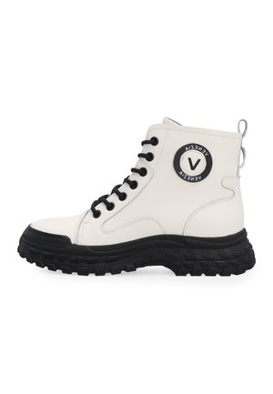 Witte hoge laars met zwarte veters, dikke robuuste zwarte zool en ronde zwart-wit logo patch op de enkel.