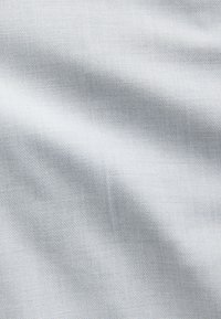 Tissu gris clair avec une texture fine tissée et des ombres subtiles indiquant de légers plis ou drapés.