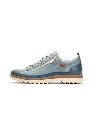 Zapatilla de cuero azul claro con acentos beiges, presenta cierre con cordones y cremallera, suelas texturizadas y un diseño estructurado.