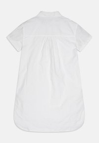 Biała sukienka koszulowa z krótkim rękawem i kołnierzykiem, z teksturowanym wzorem i marszczonym tyłem. Dół ma okrągły kształt.