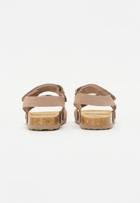 Bruna mockaskinnsandaler med justerbara remmar, korkfot sula och gummiyttersula. Bakifrån visas en enkel design med platt klack och utan dekorationer.