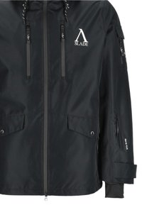 Zwarte waterdichte jas met een capuchon, voorzien van ritsen, functionele zakken en logodetails op de borst en mouw. Gladde textuur.