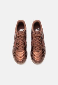 Hõbedased pruunid Nike jalgpallijalatsid, millel on paelad, vaadatuna pealt tahapoole, ühtlasel valgel taustal.