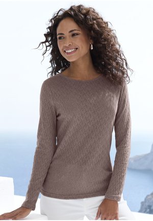 Hellbrauner Pullover mit langen Ärmeln und einem strukturierten Rautenmuster; runder Ausschnitt und schlanker Schnitt. Trägt dazu eine weiße Hose.