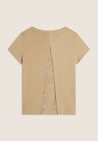 Top de manga corta beige con un corte en la parte posterior y un detalle de perforación parecido al encaje, creando un efecto de capas. Textura suave en toda la prenda.