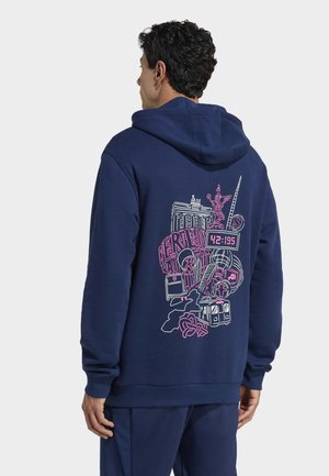 Mörkblå hoodie med dragsko i huvan, med en färgglad grafisk design på baksidan som inkluderar Berlins landmärken och konstnärliga element.