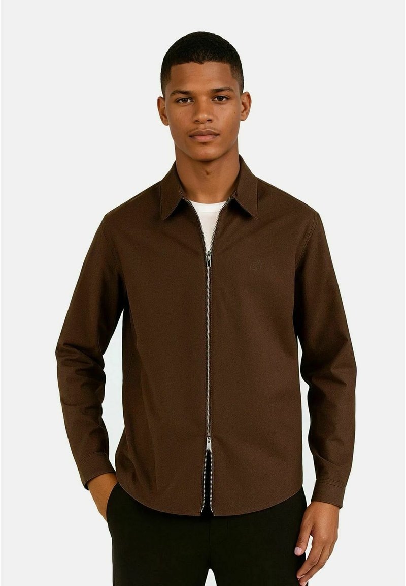 Brun zip-up jakke med krage, lange ermer og en jevn tekstur. Har en sølvglidelås og subtil logo detalj på brystet.