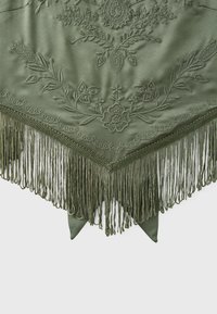 Tissu vert avec broderie florale et longues franges le long du bord pointu d'un châle ou foulard triangulaire.