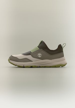 Baskets basses, à enfiler, en vert, marron et beige avec une semelle en caoutchouc et une bride élastique, arborant le logo arbre Timberland sur le côté.