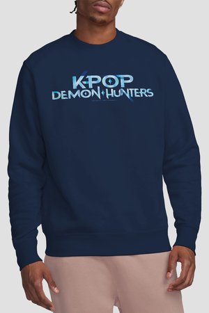 Man wearing a navy blue sweatshirt with light blue "K-POP DEMON HUNTERS" text on front, paired with light pink pants.