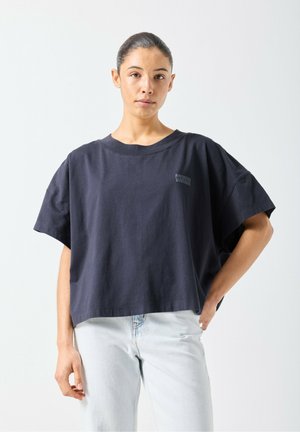 T-shirt court bleu marine en coton avec une coupe décontractée, manches courtes, large encolure et un logo discret sur la poitrine.