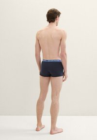 Boxer shorts navy en tissu doux avec une ceinture élastique bleue arborant le nom de la marque « TOM TAILOR » en lettres blanches.