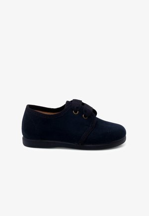Scarpe in suede blu scuro con punta arrotondata, dotate di una fascia centrale e dettagli in metallo dorato. Texture morbida con suola in gomma bassa.