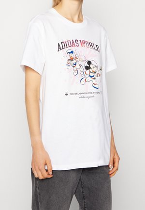 Wit T-shirt met de tekst "ADIDAS WORLD" en de tekenfilmfiguren Mickey en Donald Duck in astronautenpakken die in de ruimte zweven.