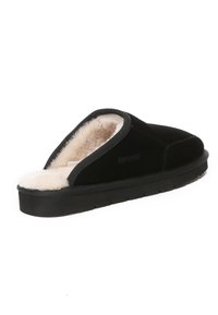 Black suede slipper with a soft cream shearling lining and a rubber sole. Open back design with subtle branding on the side.