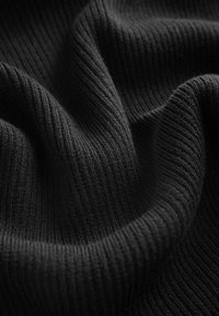 Tissu tricoté côtelé noir avec des plis doux et une texture visible en gros plan.