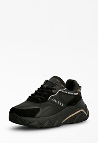 Black athletic shoes with a mix of leather and suede. Features textured rubber sole, contrasting gold accents, and prominent logo detailing.