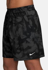 Svarta sportshorts med en texturerad, abstrakt mönstring. Elastisk midja med dragsko och vitt Nike-logotyp på nederkanten.